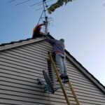 Technicians removing antenna from roof